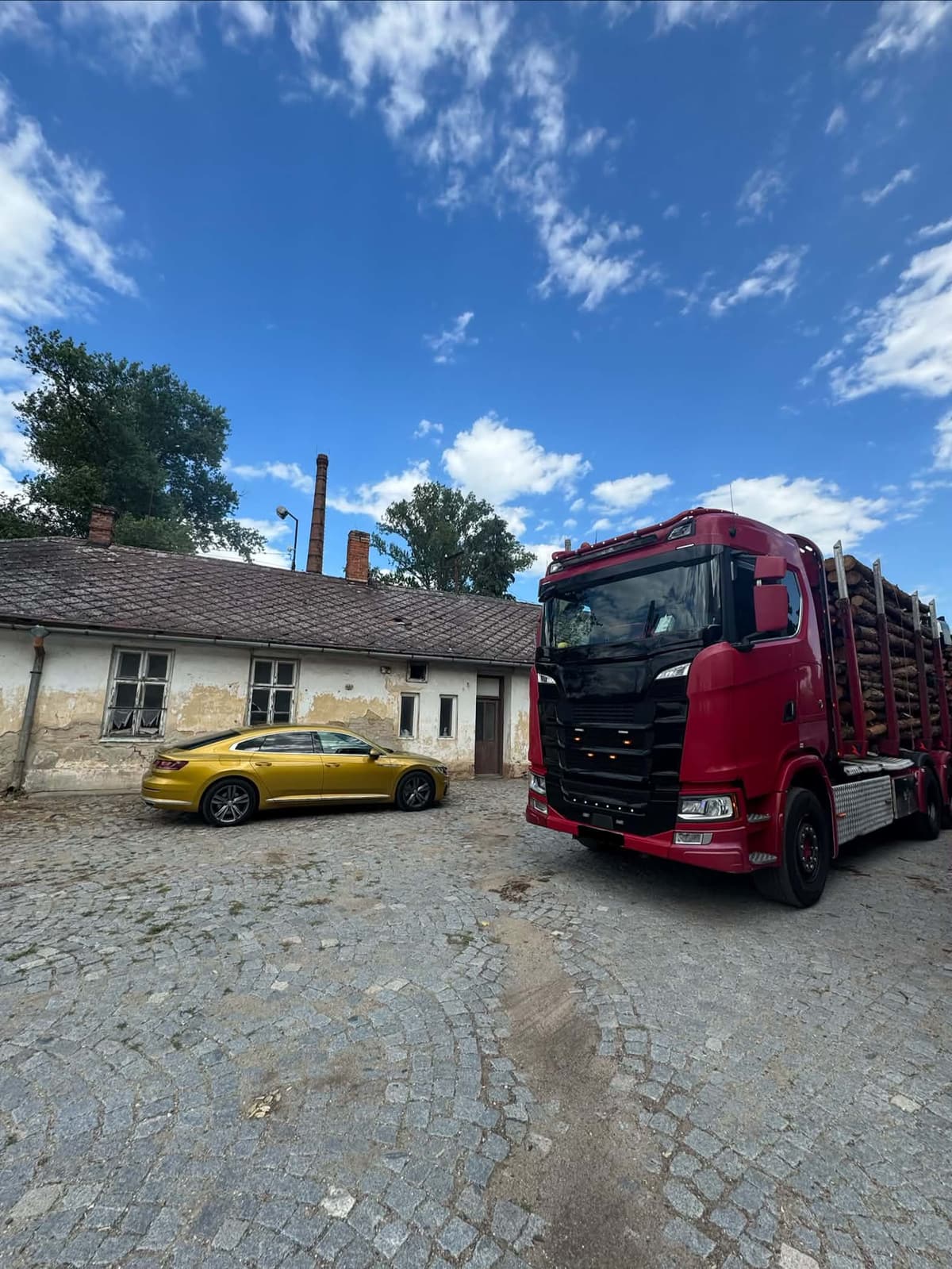 Scania s nákladem kulatiny na dvoře